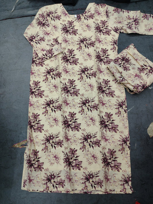 A cream-colored long kurta with a dark purple floral pattern, laid flat on a dark gray floor next to matching pleated fabric.